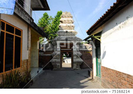 JOGJAKARTA, INDONESIA -JUNE 12, 2014: Entrance arch at old Masjid Besar Mataram Kotagede, Jogjakarta Indonesia. The arch was made from brick and hand made carving stone in traditional Balinese Style JOGJAKARTA, INDONESIA -JUNE 12, 2014: Entrance arch at old Masjid Besar Mataram Kotagede, Jogjakarta Indonesia. The arch was made from brick and hand made carving stone in traditional Balinese Style 75168214