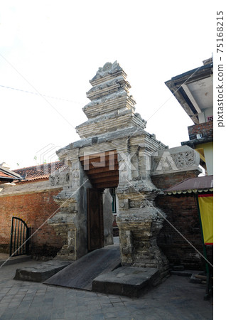 JOGJAKARTA, INDONESIA -JUNE 12, 2014: Entrance arch at old Masjid Besar Mataram Kotagede, Jogjakarta Indonesia. The arch was made from brick and hand made carving stone in traditional Balinese Style JOGJAKARTA, INDONESIA -JUNE 12, 2014: Entrance arch at old Masjid Besar Mataram Kotagede, Jogjakarta Indonesia. The arch was made from brick and hand made carving stone in traditional Balinese Style 75168215