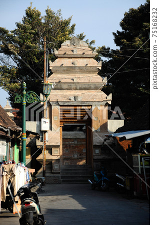 JOGJAKARTA, INDONESIA -JUNE 12, 2014: Entrance arch at old Masjid Besar Mataram Kotagede, Jogjakarta Indonesia. The arch was made from brick and hand made carving stone in traditional Balinese Style JOGJAKARTA, INDONESIA -JUNE 12, 2014: Entrance arch at old Masjid Besar Mataram Kotagede, Jogjakarta Indonesia. The arch was made from brick and hand made carving stone in traditional Balinese Style 75168232