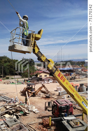 JOHOR, MALAYSIA -MAY 16, 2017: Construction workers standing in the mobile crane bucket while working at high level in the construction site. The bucket movement control by the workers himself.    75170142