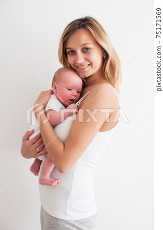 Pretty young smiling mother holding newborn baby Pretty young smiling mother holding newborn baby 75171569