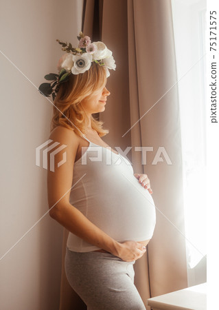 Pregnant woman stay in the room and look at the window 75171575