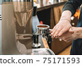The barista temps the coffee before brewing a great fragrant, fresh espresso 75171593