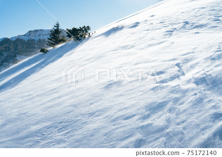 Blowing snow over snowy surface on top of mountain in Switzerland - snowstorm Blowing snow over snowy surface on top of mountain in Switzerland - snowstorm 75172140