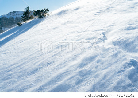Blowing snow over snowy surface on top of mountain in Switzerland - snowstorm Blowing snow over snowy surface on top of mountain in Switzerland - snowstorm 75172142