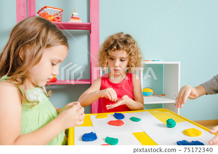 The kids sit at the desk and molding clay 75172340
