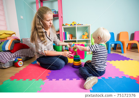 The group of kids in the kindergarten are playing with toys 75172376