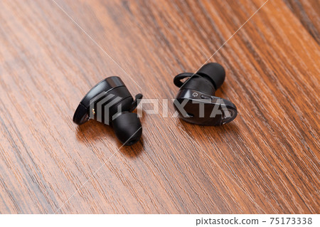 Wireless headphones on a wooden table. Headset close-up on a wooden surface. Wireless headphones on a wooden table. Headset close-up on a wooden surface. 75173338