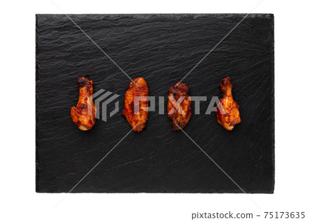 Fried wings close-up. Buffalo wings on a stone slate board isolated on white. Top view. Fried wings close-up. Buffalo wings on a stone slate board isolated on white. Top view. 75173635