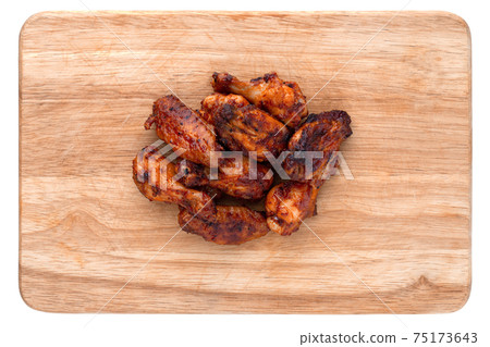 Fried wings close-up. Buffalo wings on a wooden board isolated on a white background. Top view. Fried wings close-up. Buffalo wings on a wooden board isolated on a white background. Top view. 75173643