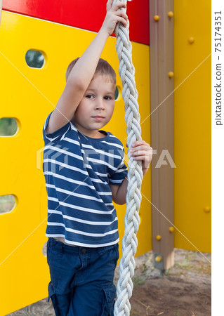 Child playing on outdoor playground. Kids play on school or kindergarten yard. Active kid on colorful monkey bars. Healthy summer activity for children. Child playing on outdoor playground. Kids play on school or kindergarten yard. Active kid on colorful monkey bars. Healthy summer activity for children. 75174351