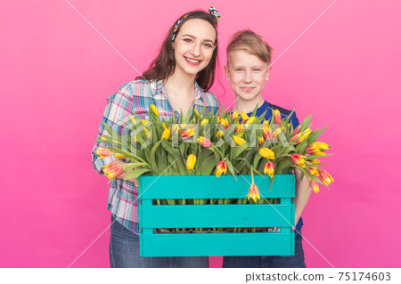 Family portrait sister and teenager brother with tulips on pink background Family portrait sister and teenager brother with tulips on pink background 75174603
