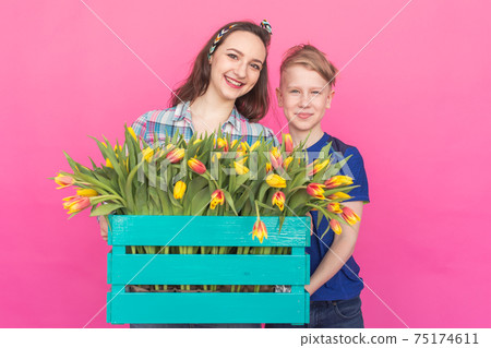Family portrait sister and teenager brother with tulips on pink background 75174611