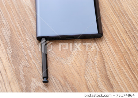 Smartphone close up. Stylus is pulled out of the connector of the device. 75174964