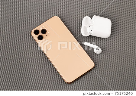 A smartphone with three cameras and wireless headphones. A smartphone with three cameras and wireless headphones. 75175240
