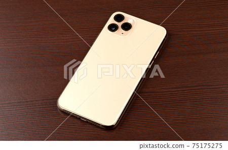Smartphone on a wooden surface. A popular smartphone close-up. Smartphone on a wooden surface. A popular smartphone close-up. 75175275