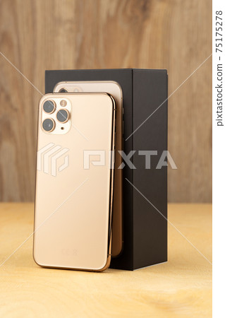 Smartphone on a wooden surface. A popular smartphone and box close-up. Smartphone on a wooden surface. A popular smartphone and box close-up. 75175278
