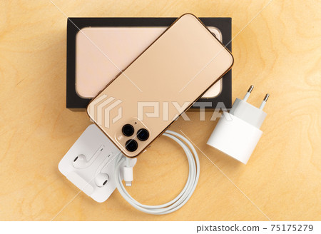 Smartphone on a wooden surface. A popular smartphone and a kit from it and a box close-up. 75175279