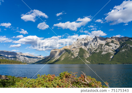 Lake Minnewanka beautiful landscape in summer day. Famous tourist attraction for leisure activities, boat cruise and mountain trail hiking in Banff National Park, Canadian Rockies. Lake Minnewanka beautiful landscape in summer day. Famous tourist attraction for leisure activities, boat cruise and mountain trail hiking in Banff National Park, Canadian Rockies. 75175343