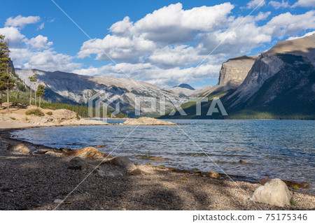 Lake Minnewanka beautiful landscape in summer day. Famous tourist attraction for leisure activities, boat cruise and mountain trail hiking in Banff National Park, Canadian Rockies. Lake Minnewanka beautiful landscape in summer day. Famous tourist attraction for leisure activities, boat cruise and mountain trail hiking in Banff National Park, Canadian Rockies. 75175346