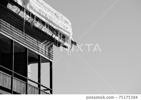 Roof with snow cornice and icicle at wooden house with balcony 75175384