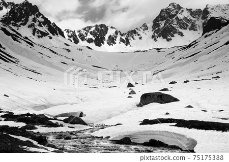 River with snow bridges in high snowy mountains at spring evening 75175388