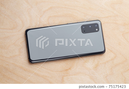 Smartphone on a wooden surface. A popular smartphone close-up. 75175423