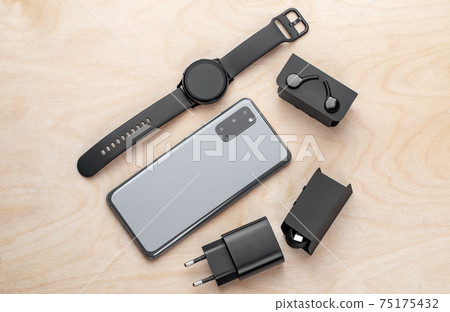 Smartphone on a wooden surface. A popular smartphone and a kit from it close-up. Smartphone on a wooden surface. A popular smartphone and a kit from it close-up. 75175432
