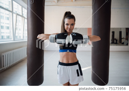 Beautiful kickboxing woman training with bag in fitness studio. 75175956