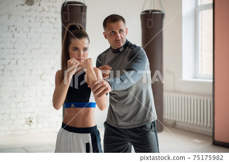 A young attractive boxing coach prepares a pretty girl for competition A young attractive boxing coach prepares a pretty girl for competition 75175982