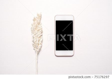 Phone with a black screen with dryed white flowers 75176297
