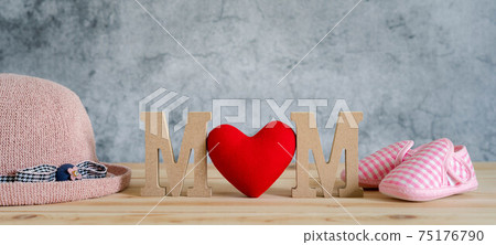 Objects on the table of decoration Happy Mother's day holiday background concept. MOM text with red heart and pink hat baby shoes. Blur grey color backdrop. Design copy space banner. Objects on the table of decoration Happy Mother's day holiday background concept. MOM text with red heart and pink hat baby shoes. Blur grey color backdrop. Design copy space banner. 75176790