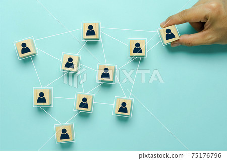 Top view of human resources and recruiting business or team leader concepts. Hand adult Asian man holding of people icon community on wooden cube block. Objects on blue paper background. copy space . 75176796