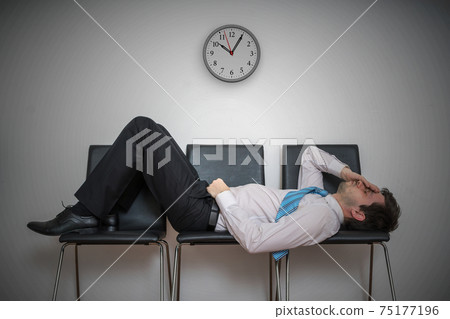 Tired bored man is sleeping in waiting room on chairs. 75177196