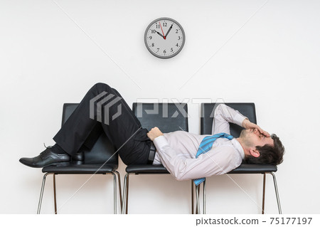 Tired bored man is sleeping in waiting room on chairs. 75177197
