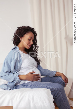 young pretty african american woman pregnant laying in bed, lifestyle people concept young pretty african american woman pregnant laying in bed, lifestyle people concept 75179444