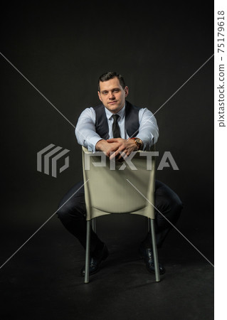 in a three-piece suit on a chair Young man three piece suit business lifestyle guy clothes. Black bodybuilder studio trendy, successful elegance background in a three-piece suit on a chair Young man three piece suit business lifestyle guy clothes. Black bodybuilder studio trendy, successful elegance background 75179618