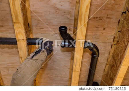 Worker using glue with fitting for installing the PVC drain pipe in the work area. Worker using glue with fitting for installing the PVC drain pipe in the work area. 75180813
