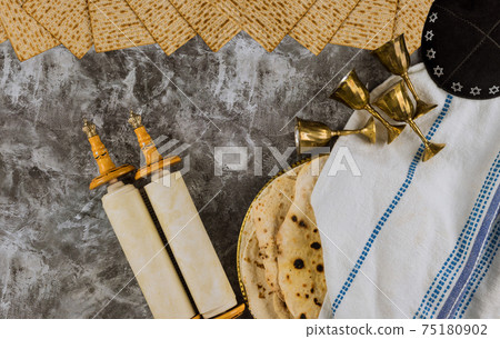 Passover day traditional celebration with cup wine and kosher matzah unleavened bread on torah scroll of Jewish holiday Pesach Passover day traditional celebration with cup wine and kosher matzah unleavened bread on torah scroll of Jewish holiday Pesach 75180902