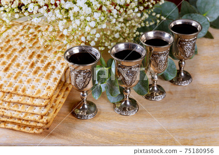 Wine with kosher four glasses a of matzah a Passover Haggadah on a wood background Wine with kosher four glasses a of matzah a Passover Haggadah on a wood background 75180956