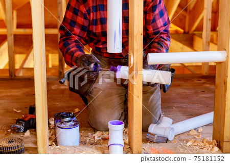 Plumbing building contractor installing plastic drain pipe in the elbow for sink drain for a custom house Plumbing building contractor installing plastic drain pipe in the elbow for sink drain for a custom house 75181152