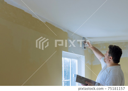 Professional construction worker applying plaster coating to the freshly plasterboard 75181157