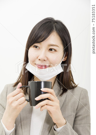 A woman drinking a drink with her mask on her chin 75183351
