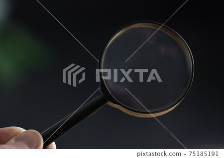 hand holding magnifying glass in dark room. concept of uncovering mystery, solve secret hand holding magnifying glass in dark room. concept of uncovering mystery, solve secret 75185191