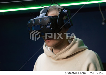 Man wearing virtual reality glasses watching 360 videos in VR gaming club 75185452