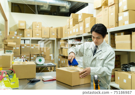 A man packing in a warehouse A man packing in a warehouse 75186987