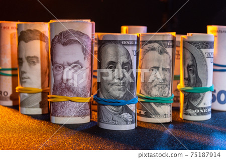 Lights of various currencies. Money rolled on the table. A lot of money. Lights of various currencies. Money rolled on the table. A lot of money. 75187914