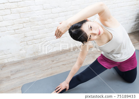 一個女人在家裡檢查姿勢時做瑜伽 75189433