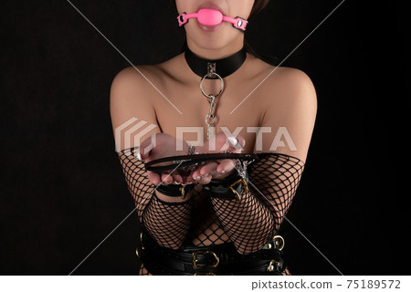 Beautiful woman in the role of a slave on a leash on black background 75189572