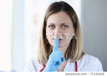 Doctor with gloves holding his index finger near his mouth 75193026